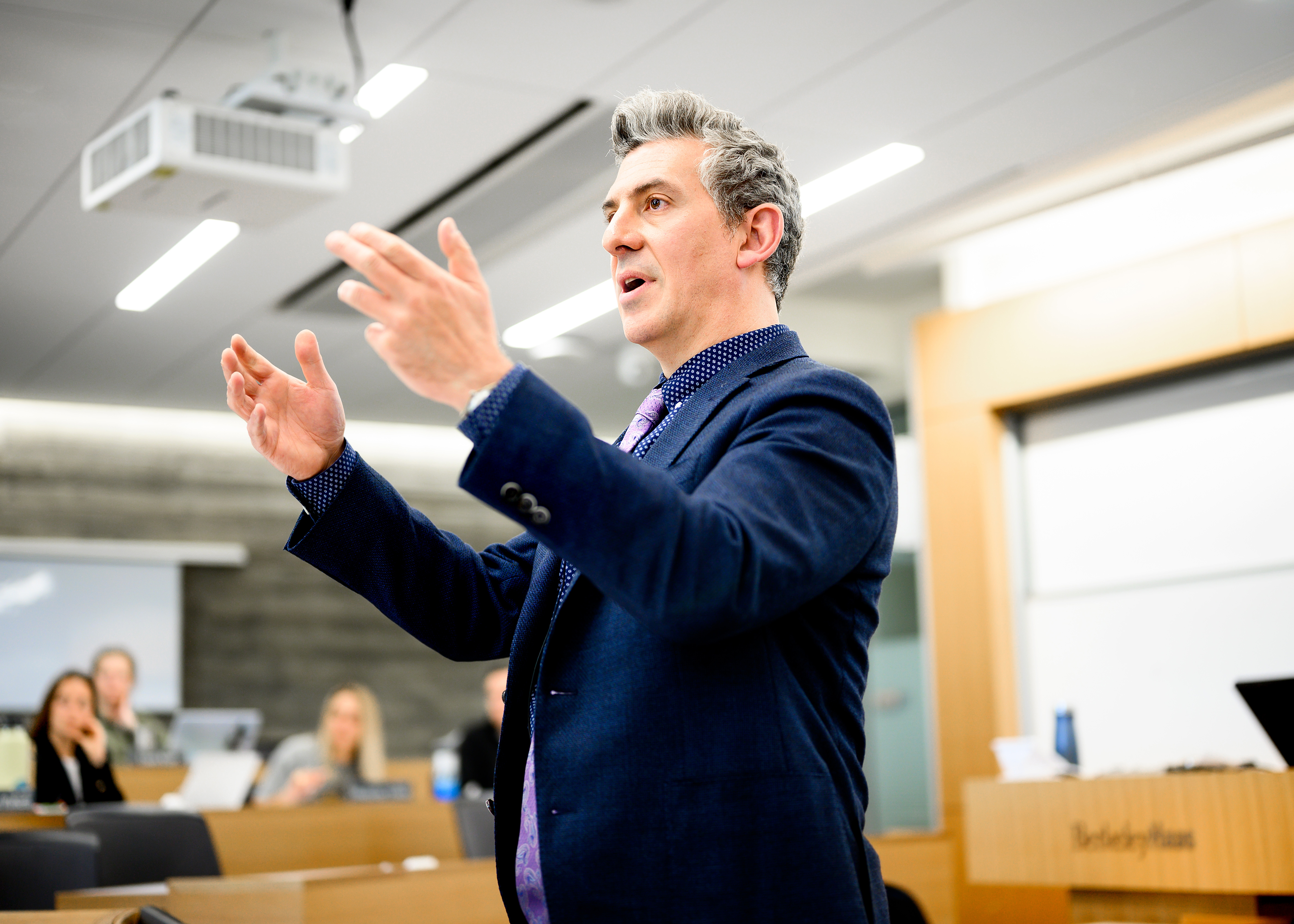 A male professor gesturing with his hands while lecturing