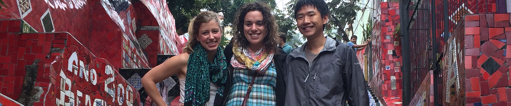 Three students by a red wall