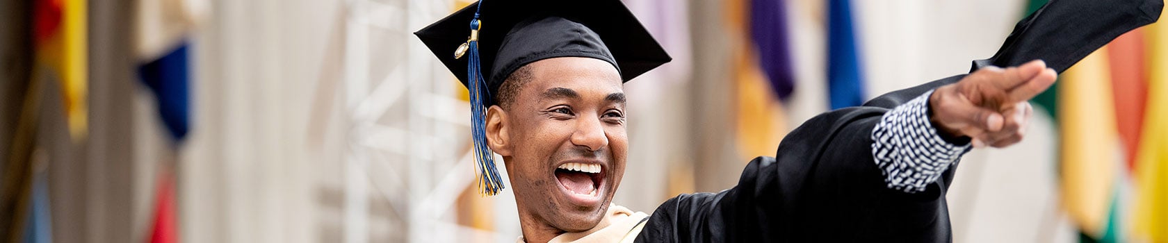 A student smiling and pointing during graduation