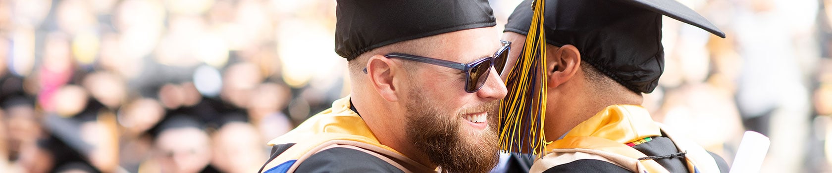 Two men embrace at graduation ceremony