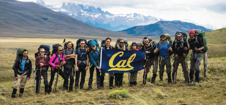 A group of hikers in the mountains holding a flag that says 